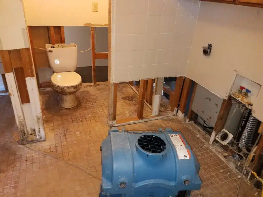 Tooele Water Damage Cleanup services from Bio Clean of Utah. A picture of a water damaged bathroom with the drywall partially removed with drying equipment
