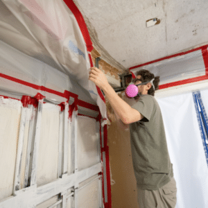 Certified mold remediation expert using plastic containment barriers.